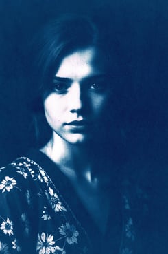 Close-up portrait of a young woman with fair skin, long straight hair, and soft lighting highlightin