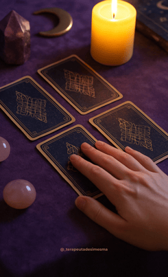 White hand over an oracle deck on a purple background, with rose quartz and symbols on the table
