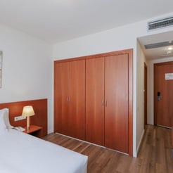 Functional hotel room setup with wardrobe and workspace for padel players