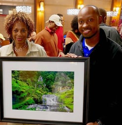 Photographer Gary Washington with collector/artist Priscilla Phifer holding Colombia Falls art.