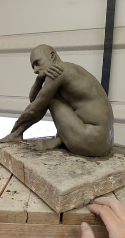 a man is sitting on a table with a sculpture of a man