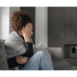 a woman sitting on a couch with her hands on her head