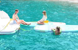 Group of friends relaxing on a boat with crystal-clear waters in the background