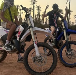 Moto cross 125 et 250 cc dans le désert marocain proche d'une palmerais