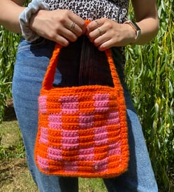 Handmade crochet shoulder bag in a green and pink checkerboard pattern