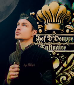 un chef en veste noire et un couteau noir à la main