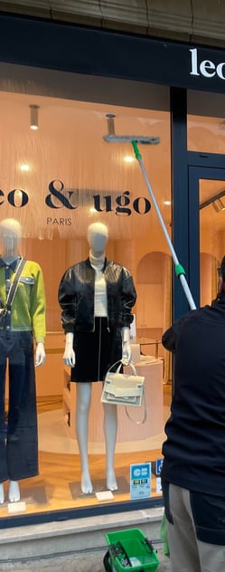Technicien de M & M Services Pro nettoyant la vitrine de la boutique Léo et Ugo à Rouen avec une rac