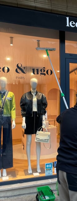 Technicien de M & M Services Pro nettoyant la vitrine de la boutique Léo et Ugo à Rouen avec une rac
