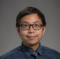 a man in a blue shirt and tie dye on a gray background