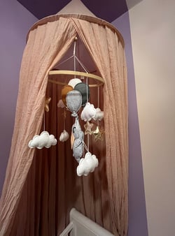Installation d’un ciel de lit avec un mobile sur le thème éléphant