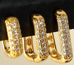 a pair of gold toned earrings with diamond set in the middle