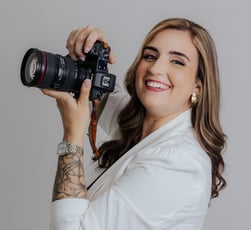 a woman holdingDébora Oliveira fotógrafa de casamentos no Rio de Janeiro a camera and smiling