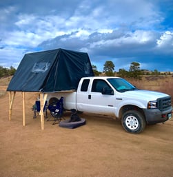 A truck with a fold-out overlanding tent on it's bed