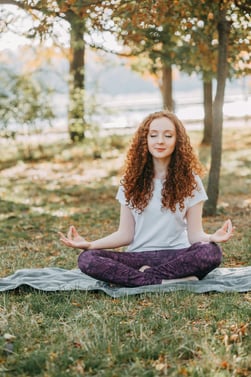 A peaceful person meditating in nature, representing the mental health benefits of meditation on Wor