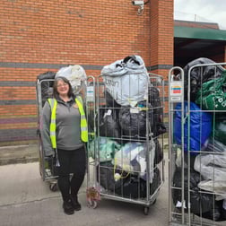 female volunteer standing near three cages of donated goods