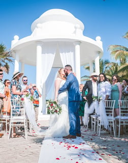 a bride and groom walking down the aisle of a beach wedding ceremony