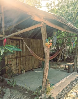 Entrada a una cabaña rústica con hamaca privada