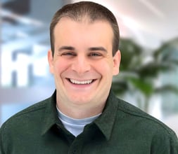 a man in a green shirt smiling at the camera