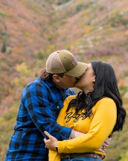 a man and woman kissing in the mountains