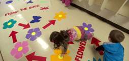 two children playing on a floor with bright flower images