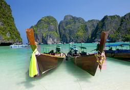 boats in the water with people on the beach