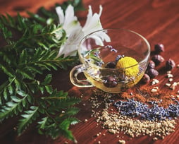 a cup of tea with on a wood table with flowers in it