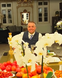 a man sitting at a table with a large vase filled with flowers