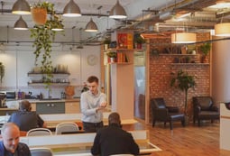 a man standing in a room with a bunch of people in a coworking place