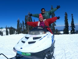 a man and a woman on a snowmobile