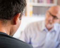 a man in a blue shirt is looking at a cell phone