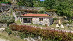 a small stone house with a red roof and a red roof