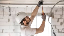 Profesional instalando sistema de iluminación en un almacén, reformas total Asturias