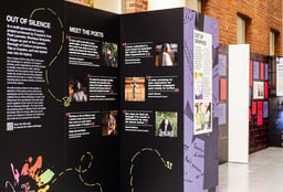 an exhibition display of photos and text on black and purple backgrounds