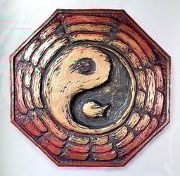 Picture of a Bague plaque. The yin-yang is in the center, surrounded by trigrams. It is red fading to gold in the center. 