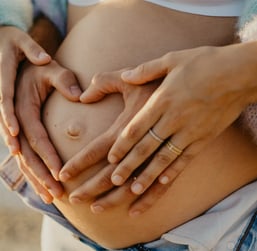 Mains des parents formant un cœur sur le ventre rond – photo de grossesse tendre dans le Gard