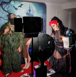 Photo booth attendant dressed in a Halloween-themed costume assisting guests in the SweetAz Co. photo booth at an event in Re