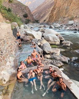 Group of friends swimming in natural pools during the Colca Canyon trek in Peru.