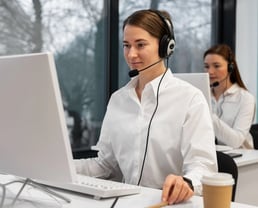 a woman in a white shirt and headphones on a computer