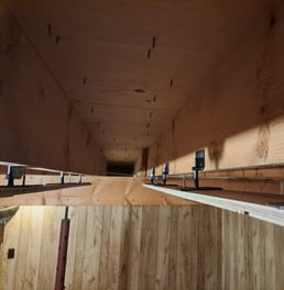 Adjustable metal brackets installed between wood joists for precision ceiling levelling in basement renovation