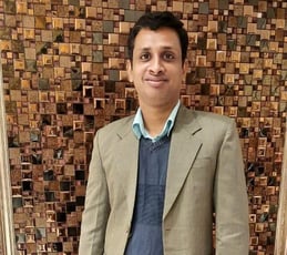 a man in a suit and tie standing in front of a wooden paneled wall