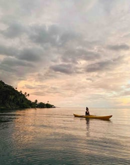 Eva canoeing during a sunset on the lagoon of Taha'a, French Polynesia.
