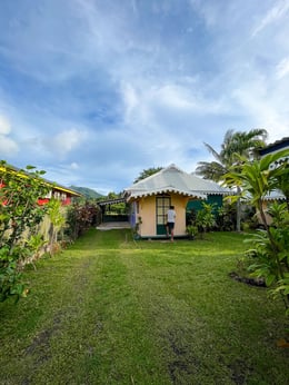 Maison d'hébergement traditionnelle entourée de verdure luxuriante sur l'île de Huahine, Polynésie française.