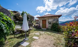 a small stone building with a white umbrella