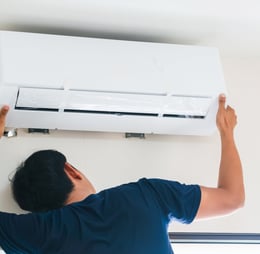 a man is fixing a air conditioner in a room