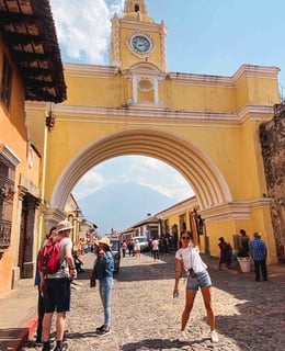 Eva in front of the iconic yellow arch of Antigua, Guatemala.