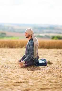 Un homme assis méditant, en pleine conscience, dans la un champ de blé