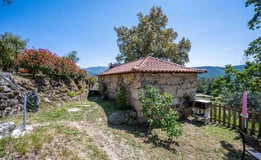 a stone building with a red roof and a wooden fence