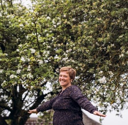 Billede af Gunda der danser foran et blomstrende æbletræ.