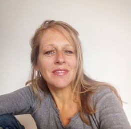 une femme blonde avec un pull gris