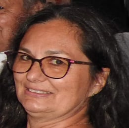 Une femme avec des cheveux brun des lunettes rouge avec un grand sourire 